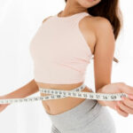 여자가 줄자로 허리사이즈를 재고 있는데 다이어트에 성공했는데 줄자가 넉넉히게 남아있다.